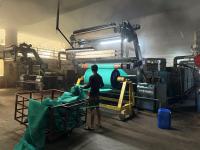 Factory worker in a Textil MSME collects cloth from a big drum.