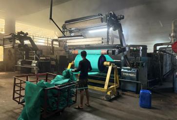 Factory worker in a Textil MSME collects cloth from a big drum.