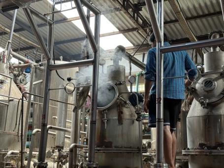 Steam emitting from a machine at a textile MSME while workers stand next to it.