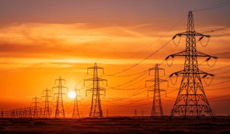 Pylons and electrical supply lines with a flaming sunset background