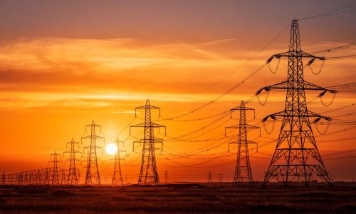 Pylons and electrical supply lines with a flaming sunset background