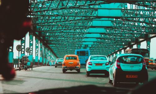 A road in Kolkata city with yellow taxis, transport corporation buses and cars.