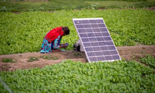 A girl charges her smart phone using solar energy. Photo by Pradeep Gaurs/Shutterstock
