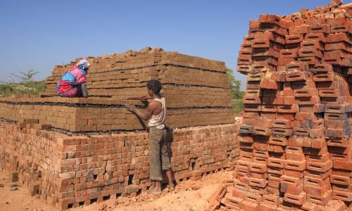 Workers arrange raw clay bricks manually for baking. Photo by Hari Mahidhar/Shutterstock.